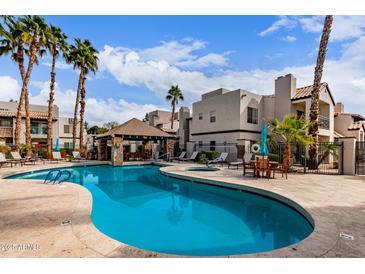 Stunning community pool with a beautiful seating area, swaying palm trees, and appealing architecture at 14145 N 92Nd St # 1031, Scottsdale, AZ 85260