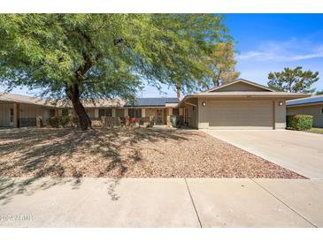 Charming single-story home featuring a well-kept yard, mature trees, and a two-car garage at 14633 N Boswell Blvd, Sun City, AZ 85351