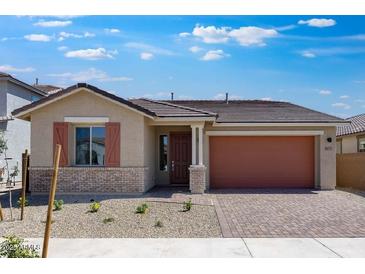 Inviting single-story home featuring desert landscaping, a brick-accented facade, and a brick paver driveway at 14777 W Soft Wind Dr, Surprise, AZ 85387