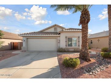 Charming single-story home with a two-car garage, desert landscaping, and a mature palm tree at 15911 W Carmen Dr, Surprise, AZ 85374