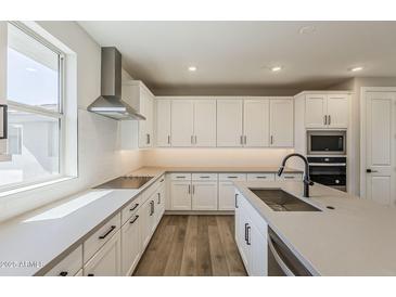 Bright kitchen features white cabinets, stainless appliances, large island and hardwood flooring at 2121 W Sonoran Desert Dr # 45, Phoenix, AZ 85085