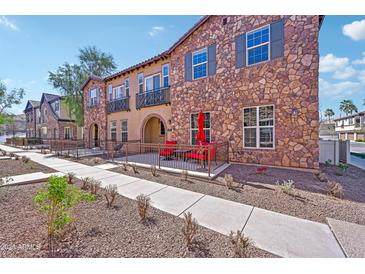 Charming townhome featuring stone accents and a cozy patio with red seating, perfect for outdoor relaxation at 2727 S Equestrian Dr # 103, Gilbert, AZ 85295
