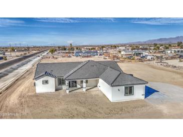 A charming single-story home with a gray tiled roof sits on a large lot ready for landscaping at 30634 W Latham St, Buckeye, AZ 85326