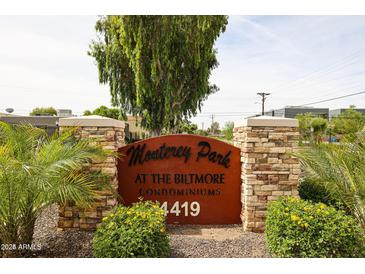 View of the 'Monterey Park At The Biltmore Condominiums' community sign with mature landscaping and stone accents at 4419 N 27Th St # 8, Phoenix, AZ 85016