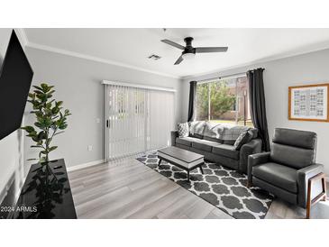 Bright living room featuring a comfortable gray sofa, stylish patterned rug, and sliding glass doors at 5345 E Van Buren St # 141, Phoenix, AZ 85008