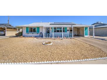 Charming home featuring a covered front porch, rock landscaping, and solar panels on the roof at 11407 N 111Th Ave, Sun City, AZ 85351