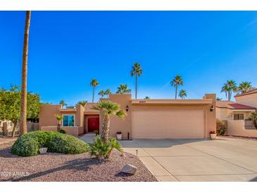 Charming single-story home featuring a spacious two car garage, mature landscaping, and a red double door entrance at 26401 S Brentwood Dr, Sun Lakes, AZ 85248