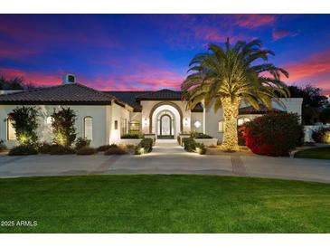 Stunning home exterior at dusk with a well-manicured lawn, inviting entrance and a lovely illuminated palm tree at 13670 N 85Th Pl, Scottsdale, AZ 85260