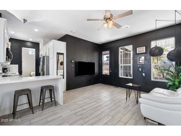 Modern living room featuring dark painted brick wall, neutral floors, and bright white kitchen bar at 201 S Greenfield Rd, Mesa, AZ 85206