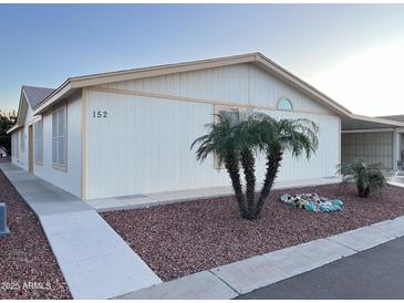 Charming single-level home with a well-maintained yard and desert landscaping featuring decorative rocks and palm trees at 437 E Germann Rd # 152, San Tan Valley, AZ 85140