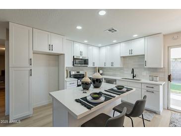 Updated kitchen with white cabinetry, modern appliances, and a functional center island with seating at 4932 W Golden Ln, Glendale, AZ 85302