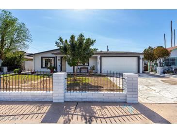 Charming single-story home featuring a xeriscaped front yard, iron fencing, and attached two-car garage at 5223 W Lewis Ave, Phoenix, AZ 85035