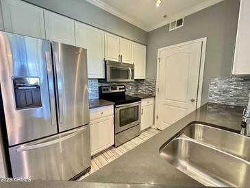 Modern kitchen featuring stainless steel appliances, white cabinets, gray backsplash and sink at 1701 E Colter St # 226, Phoenix, AZ 85016