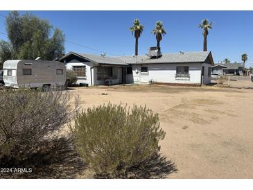 Modest single story home with desert landscaping and white exterior paint beneath a bright, cloudless sky at 2201 W Washington St, Phoenix, AZ 85009