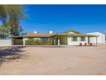 Charming single-story home featuring a cozy front yard and covered parking area under a bright sky at 22102 W Ripple Rd, Buckeye, AZ 85326