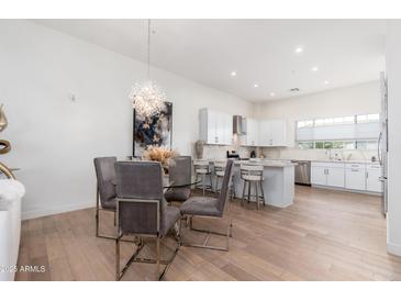 Open-concept dining area with a glass-top table, stylish chairs, and modern chandelier lighting at 4438 N 27Th St # 24, Phoenix, AZ 85016