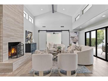 Bright living room features vaulted ceilings, modern fireplace, stylish furniture and sliding barn doors at 10435 N 98Th St, Scottsdale, AZ 85258