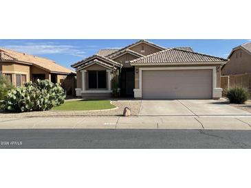 Charming single-story home with a well-maintained lawn, desert landscaping, and a two-car garage at 12565 W Amelia Ave, Avondale, AZ 85392