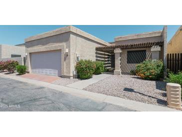 Charming single-story home with a two-car garage, desert landscaping, and inviting pergola-covered entrance at 1360 E Brown Rd # 9, Mesa, AZ 85203