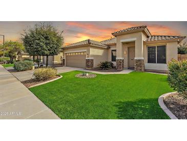 Charming single-story home with a well-manicured front yard and tile roof at sunset at 16847 W Marconi Ave, Surprise, AZ 85388