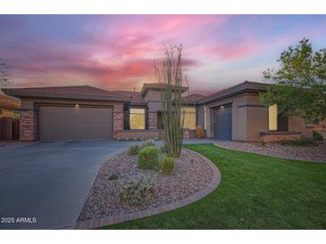 Charming single-story home featuring a lush green lawn, rock garden, and a spacious three-car garage at 40930 N Lambert Trl, Phoenix, AZ 85086