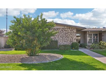 Charming home with a well-maintained lawn and mature landscaping featuring a brick facade at 10533 W Granada Dr, Sun City, AZ 85373