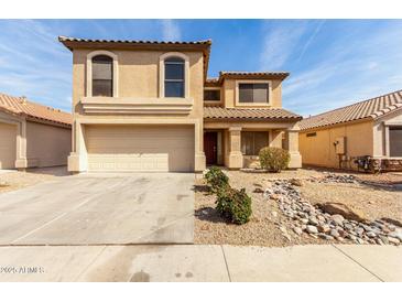 Charming two-story home featuring a tile roof, arched windows, and a two-car garage with a desert landscape at 21397 N Goles Dr, Maricopa, AZ 85138