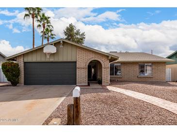 Charming brick home featuring a spacious garage, front yard, and an arched doorway, with a mailbox near the driveway at 2671 W Bentrup St, Chandler, AZ 85224