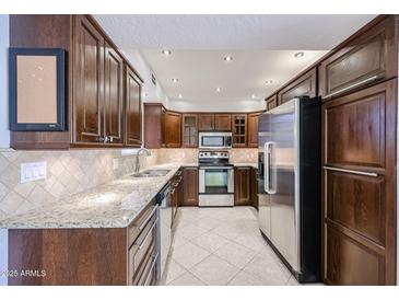 Charming kitchen featuring stainless steel appliances, granite countertops, and tiled backsplash at 7800 E Lincoln E Dr # 1102, Scottsdale, AZ 85250