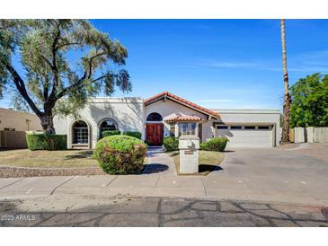 Charming home featuring mature tree, arched windows and tiled roof, offering timeless curb appeal at 10540 N 78Th Pl, Scottsdale, AZ 85258