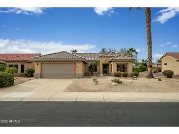 Charming single-story home featuring a desert landscape, neutral stucco, and a two-car garage with a tile roof at 16051 W Desert Winds Dr, Surprise, AZ 85374