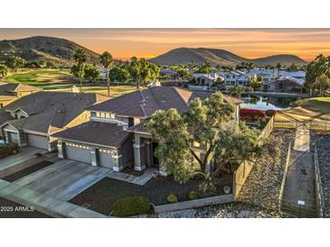 Stunning two-story home boasts lush landscaping, mature trees, and a charming water feature against a picturesque mountain backdrop at 21915 N 65Th Ave, Glendale, AZ 85310