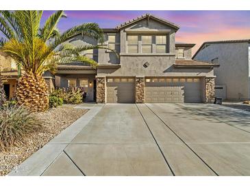 Two story stucco home with a three car garage, desert landscaping, and a large palm tree at 29740 W Fairmount Ave, Buckeye, AZ 85396