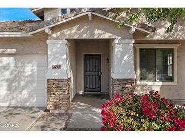 Close-up of home's entrance with stone accents on columns, bougainvillea and a well-manicured lawn at 3746 E Vallejo Dr, Gilbert, AZ 85298