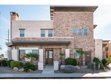 Stunning stone house with desert landscaping, covered entry, and modern architectural details at 4931 N Woodmere Fairway -- # 1001, Scottsdale, AZ 85251