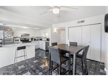 Bright kitchen area featuring white cabinetry, stainless steel appliances, and dining table with modern chairs at 6345 N 49Th Ave, Glendale, AZ 85301