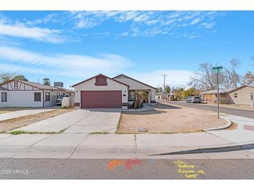 Charming single-story home features a red garage door and a well-maintained front yard, complemented by a clear blue sky at 7510 N 59Th Ln, Glendale, AZ 85301