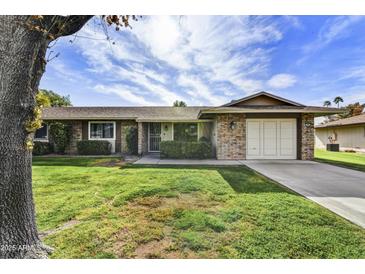 Charming brick home featuring a well-manicured lawn and mature shade tree at 9813 W Pleasant Valley Rd, Sun City, AZ 85351