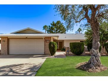 Charming single-Gathering home with a lush green lawn, mature trees, and a welcoming two-car garage at 12633 W Brandywine Dr, Sun City West, AZ 85375