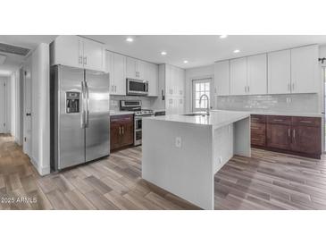 Bright kitchen features white cabinetry, stainless steel appliances, and spacious island with quartz countertops at 2447 E La Jolla Dr, Tempe, AZ 85282