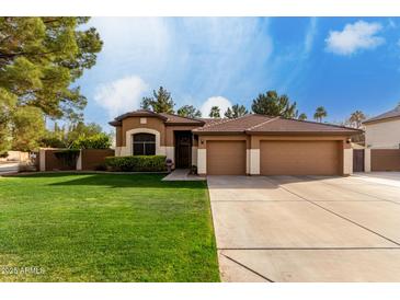 Charming single-story home with a well-manicured lawn and three-car garage at 265 E Liberty Ln, Gilbert, AZ 85296