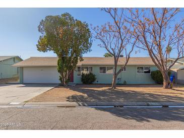 Charming single story home with a two-car garage, mature trees, and an inviting front yard at 3925 W Harmont Dr, Phoenix, AZ 85051