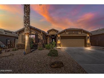 Beautiful single-story home showcasing desert landscaping and a neutral color palette under a vibrant sunset sky at 42660 W Oakland Dr, Maricopa, AZ 85138