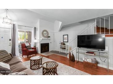 Cozy living room featuring a fireplace, hardwood floors, a plush sofa, and a sliding glass door at 1211 N Miller Rd # 258, Scottsdale, AZ 85257