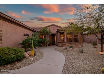 Well-manicured home featuring desert landscaping with cacti, palm trees and a stone pathway to the front door at 15131 W Daybreak Dr, Surprise, AZ 85374