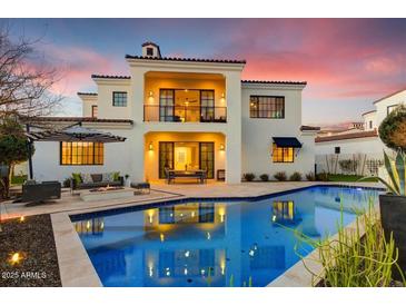 Beautiful backyard with a refreshing blue pool, dining, lounge furniture, and a two-story white stucco home at 9467 E Rockwood Dr, Scottsdale, AZ 85255