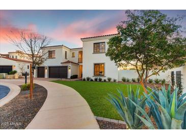 Stunning two-story home featuring a paved walkway, lush lawn, and dark brown accents on the garage doors and window frames at 9467 E Rockwood Dr, Scottsdale, AZ 85255