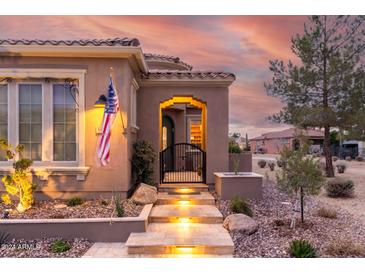 Inviting home exterior with illuminated entry stairs, desert landscaping, and a charming front gate at 1407 E Artemis Trl, San Tan Valley, AZ 85140
