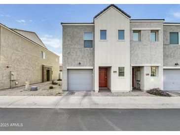 View of townhome with gray stucco, white trim, brown door, garage, and rock landscaping at 2181 W Harmont Dr, Phoenix, AZ 85021