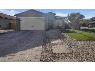 Charming home featuring a two-car garage, low maintenance landscaping, and a stone paver driveway and walkway at 2297 E Mews Rd, Gilbert, AZ 85298